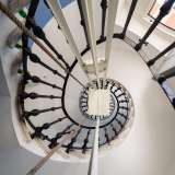 Alziamo lo sguardo restando incantati dalla visuale a spirale della rampa di scale che circonda un meccanismo a corda che corre lungo tutta la colonna centrale